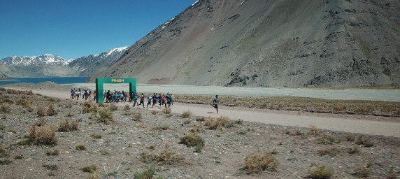 Man running and passing finish line by mountains
