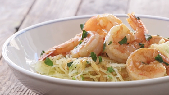 A bowl filled with spaghetti squash, jumbo shrimp and sprinkles of cilantro.