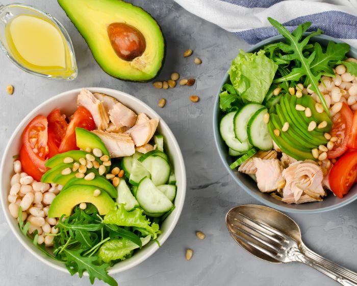 A bowl filled with a colorful salad mixture of mixed greens, red onions and avocado.
