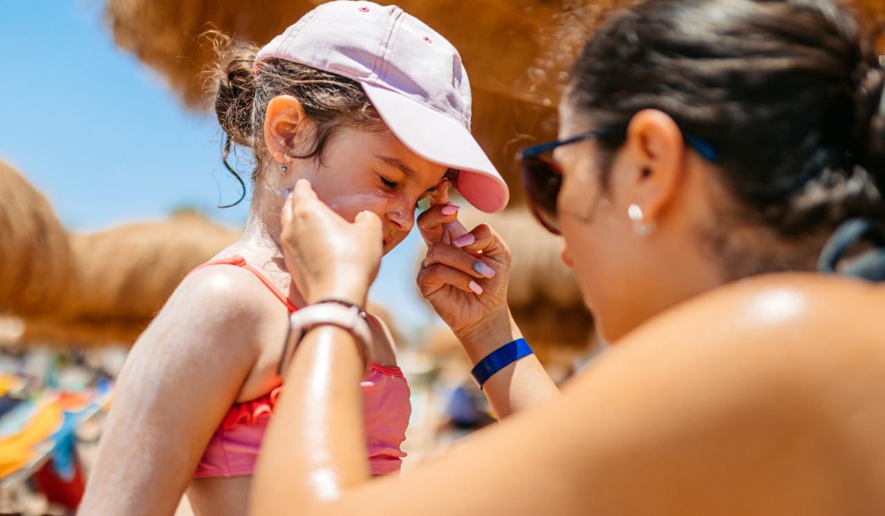 A woman applying sunscreen to child