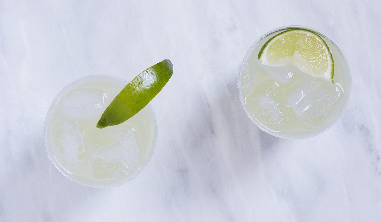 An aerial view of two drinks with limes.