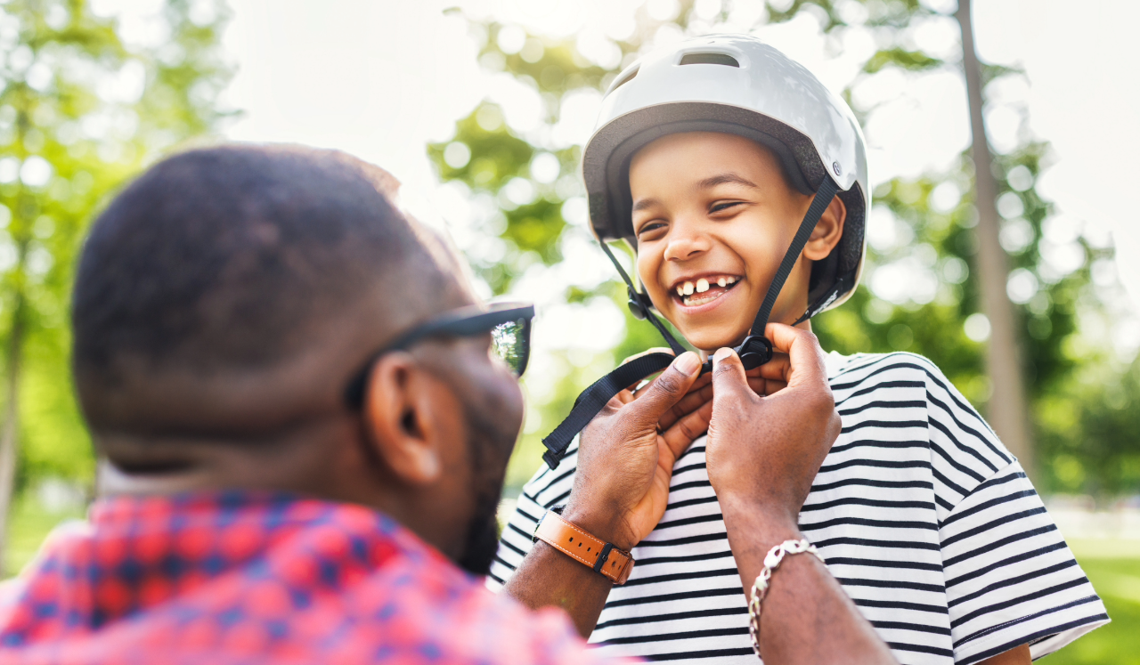 Parent strapping bike helmet to child's head.