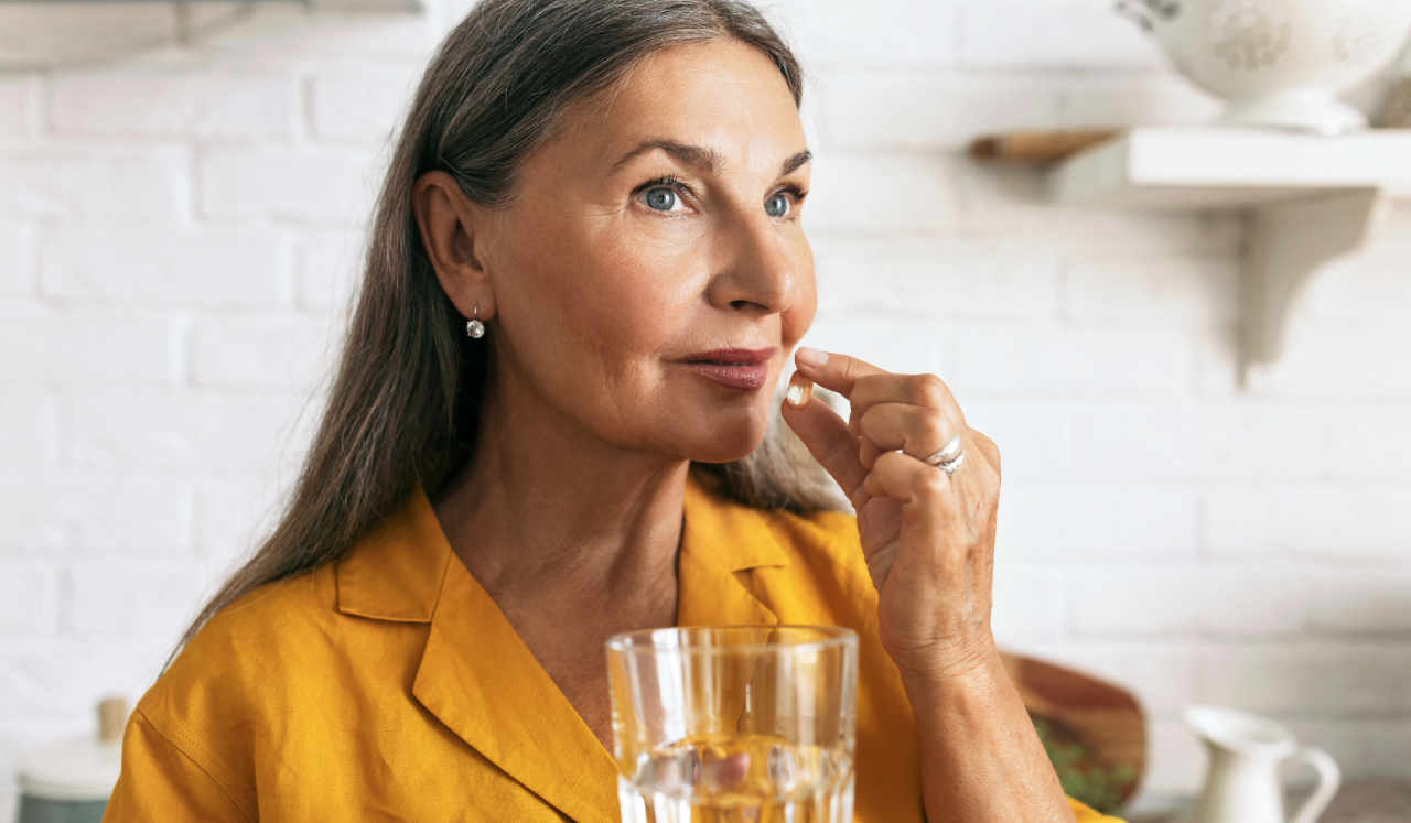 Woman taking pill with larger glass of water