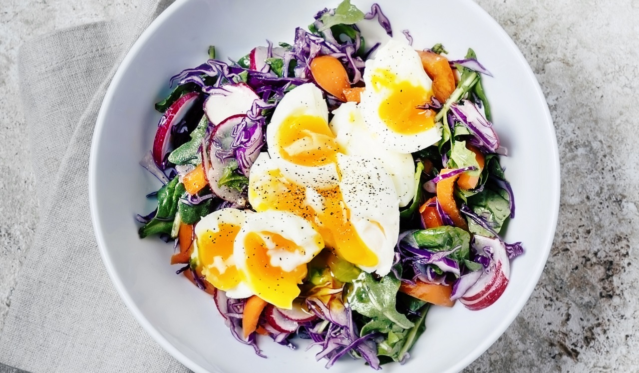 A bowl of salad topped with eggs.