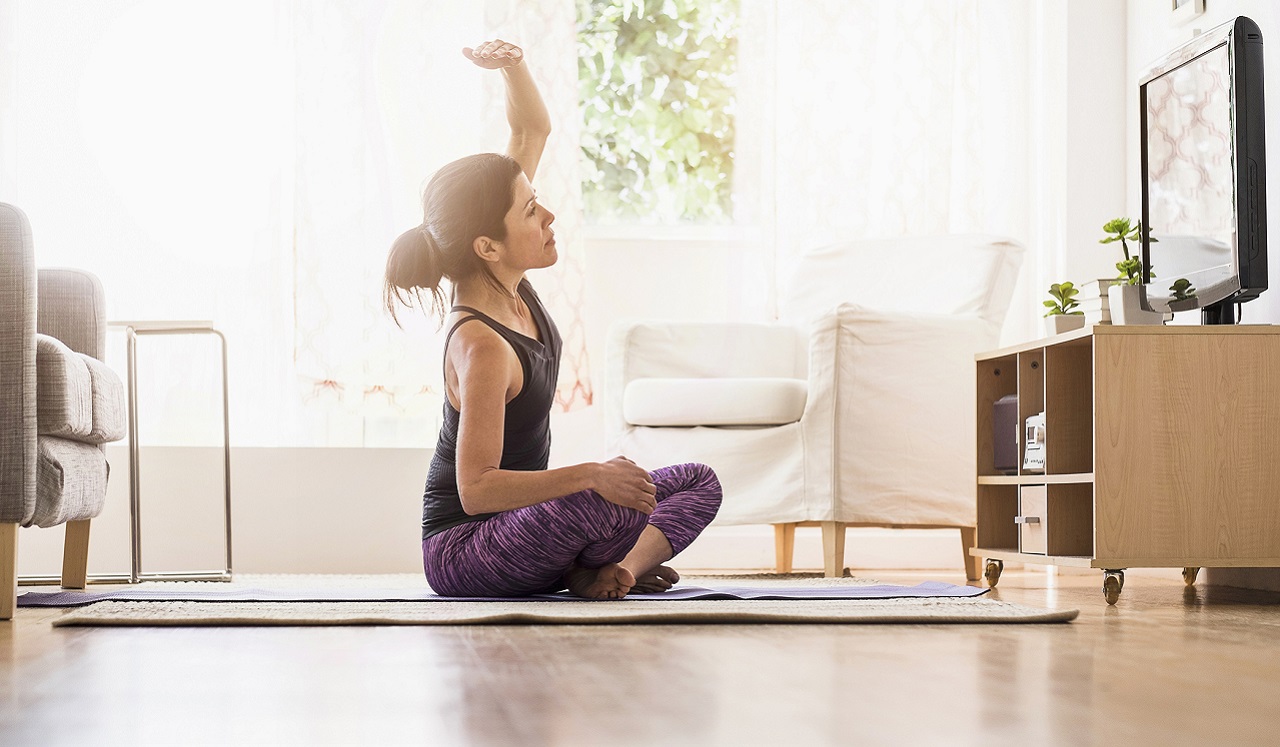 A woman following a yoga practice from her television.