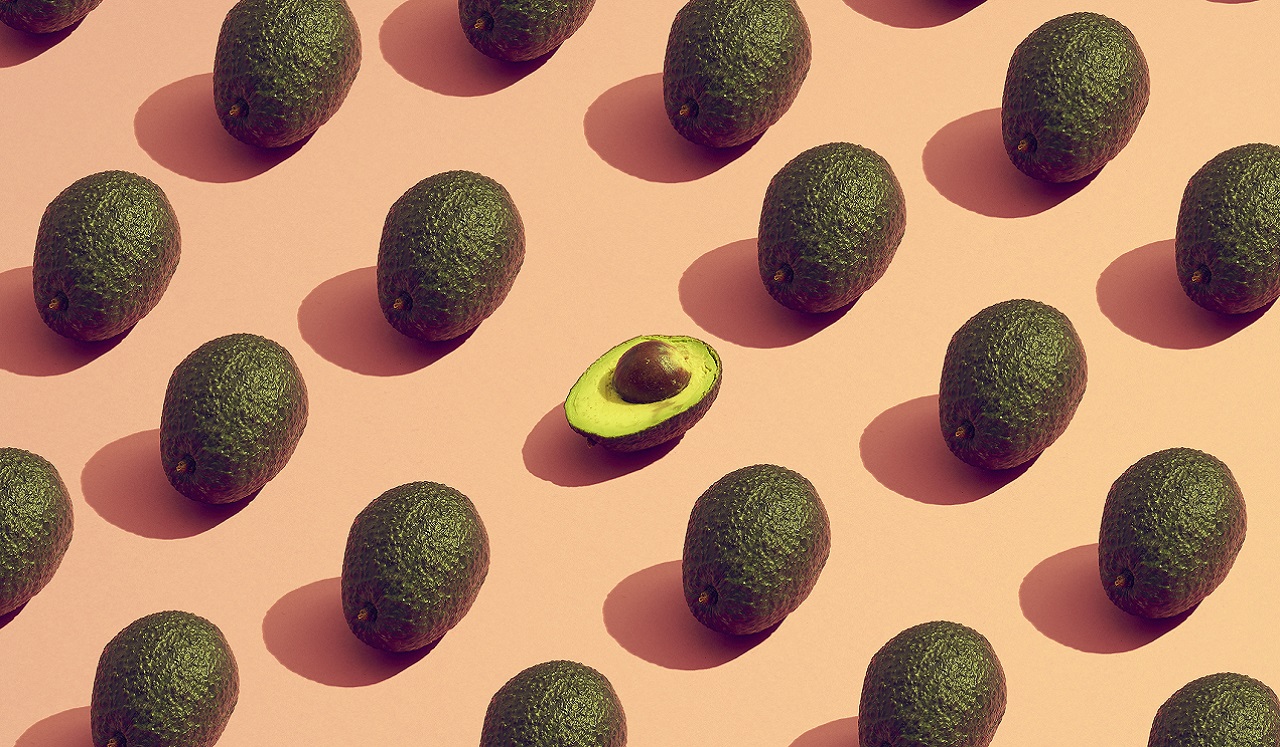 Avocados arranged in a pattern along a pink backdrop