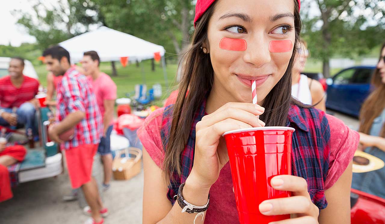 A girl at tailgate is drinking from a solo cup.