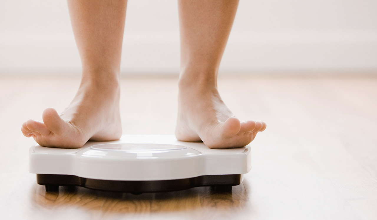 A person steps on to a white bathroom scale.