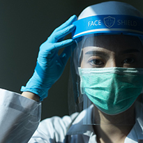 A physician wearing a mask also dons a face shield. 