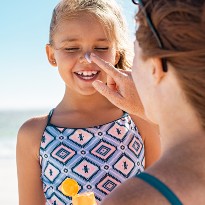 Parent applying sunscreen on their child at the beach