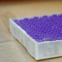 A tray of purple-topped medical vials