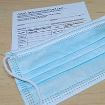 A vaccination record card and face mask on a table.