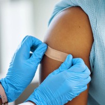 Doctor placing band-aid on patients shoulder