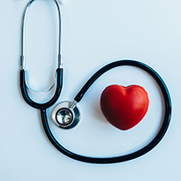 A stethoscope artistically wrapped around a toy heart.