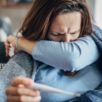Woman coughing and checking temperature