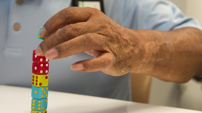 A TIRR Memorial Hermann rehabilitation patient stacks dice to work on fine motor skills.