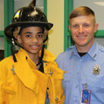 Boy dressed as firefighter with real firefighter