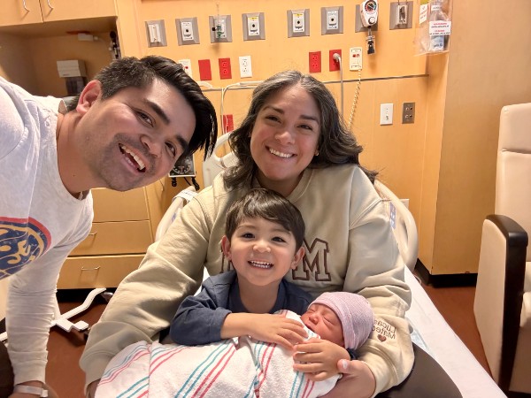 family smiling in hospital bed
