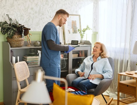 A woman is supported by a caregiver in her home. 