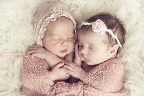 Twin babies sleeping and holding hands