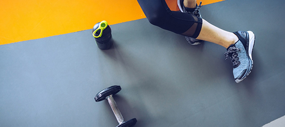 A woman and a hand weight on a workout mat