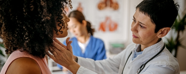 doctor checking woman's thyroid