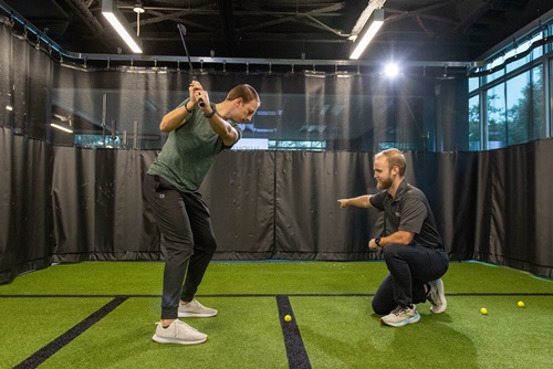 Patient practicing golf swing with therapist.