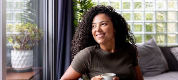 Woman looking out window drinking coffee