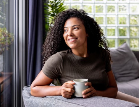 Woman looking out window drinking coffee