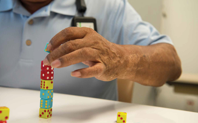 TIRR Memorial Hermann patient, Hector Alvarez, carefully stacks dice as part of physical therapy.