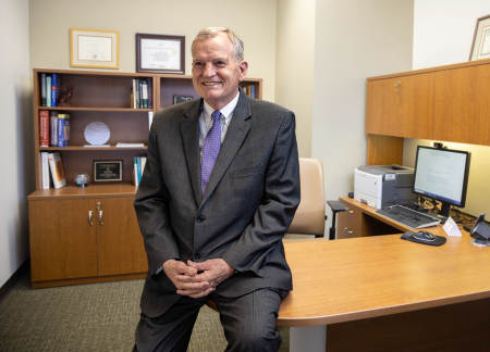 Mark Sherer smiles at his desk in his office at TIRR Memorial Hermann