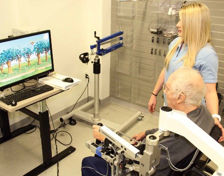 A TIRR Memorial Hermann medical professional assists in rehabilitation using technology.