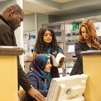 Medical professionals collaborate around a computer.