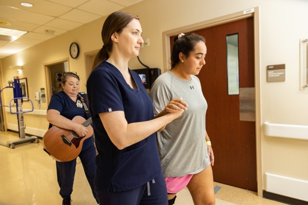 TIRR Memorial Hermann therapist and patient walk through the Stroke therapy hallway.