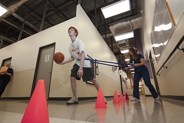 A teenager works with a basketball down the hall.