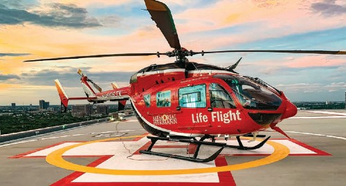 The Memorial Hermann Life Flight helicopter sits on the helipad below a sunset-colored sky.