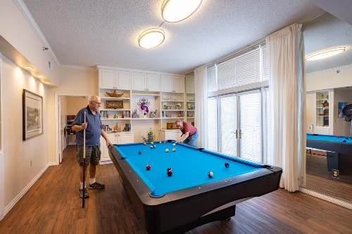 Residents of Memorial Hermann University Place play pool together in the game room.
