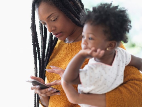 Mom using phone and holding daughter