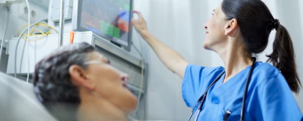 A physician looks at patient's vitals in a hospital setting