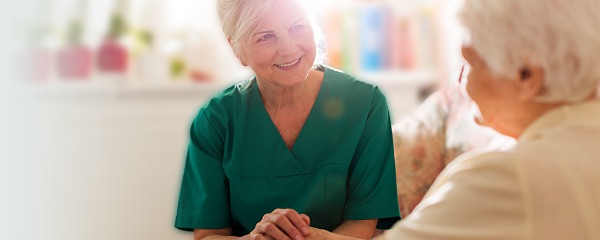 A clinical worker holds the hands of an elderly woman while in conversation