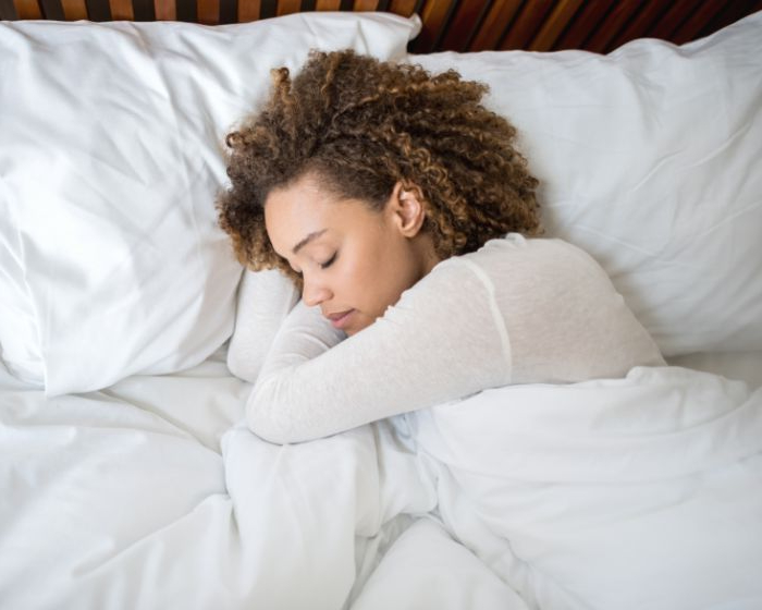 A woman lays sleeping in a cozy bed. 