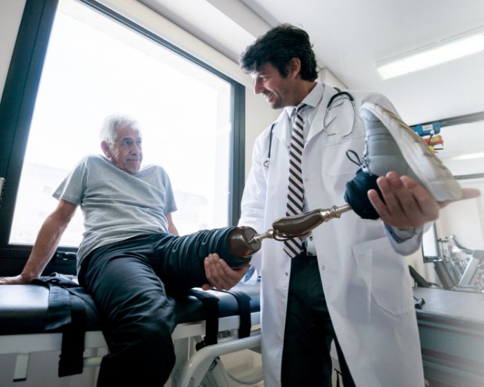 A physician helps a patient with a prosthetic leg.
