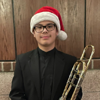 Jacob Velez shows his musical instrument while wearing a Christmas hat