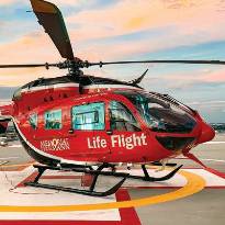 The Memorial Hermann Life Flight helicopter sits on the helipad below a sunset-colored sky.